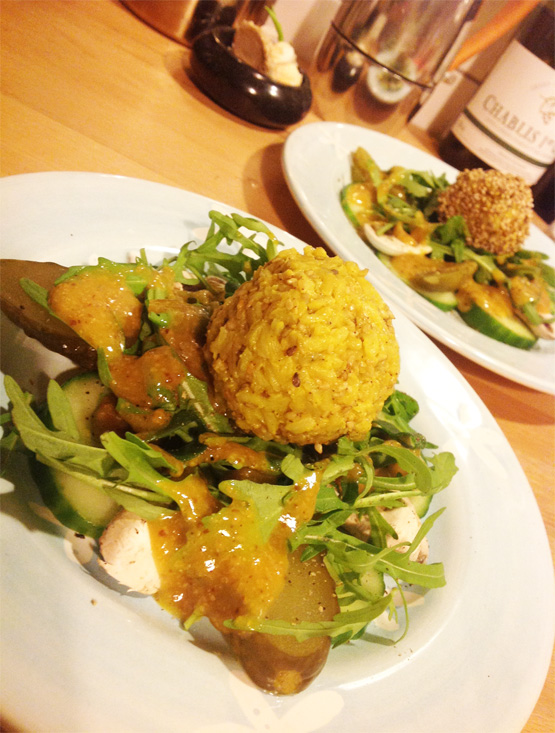 Goldene Reisbällchen auf Rucolasalat mit Salzgurken und Champignons